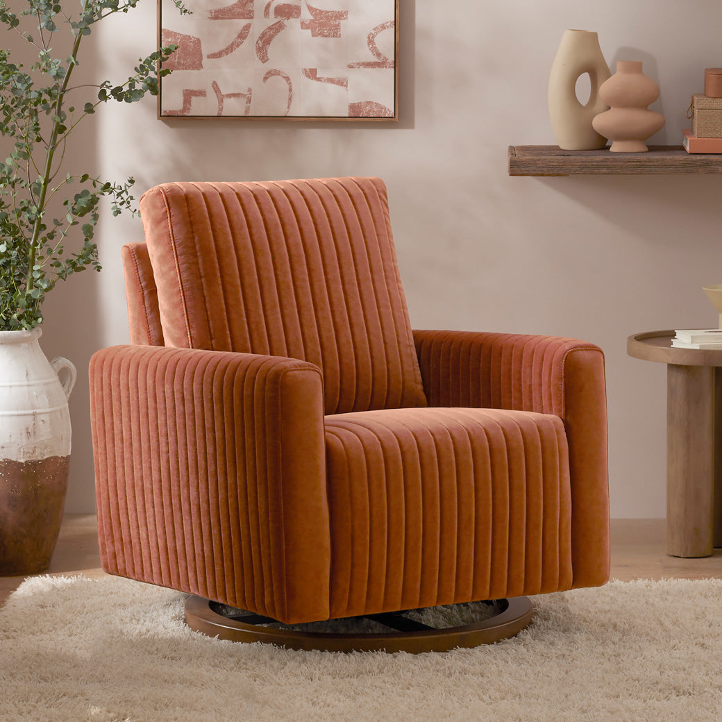 Babyletto Poe Channeled Swivel Glider next to plant and coffee table  in -- Color_Rust Velvet with Dark Wood Base