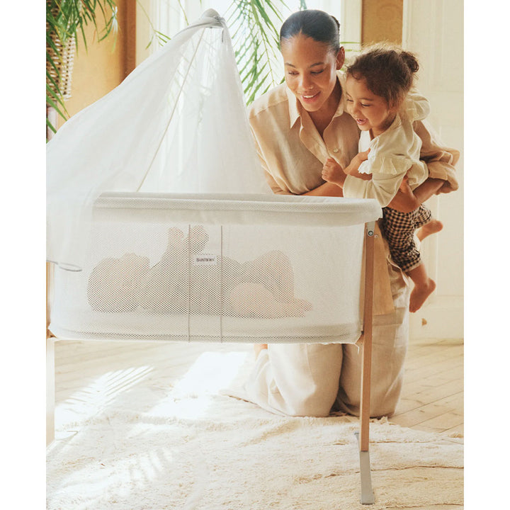 Mom and toddler looking at baby in BABYBJÖRN Cradle