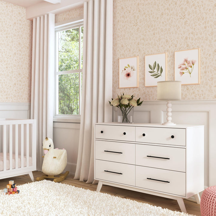 DaVinci Otto 6-Drawer Dresser next to a swan rocker and crib  in -- Color_White