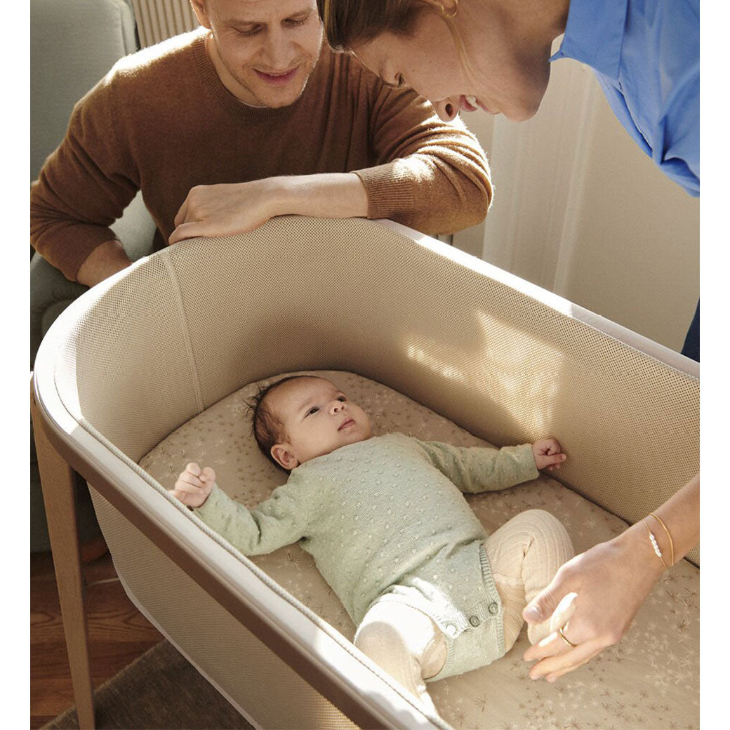 Baby in Stokke Snoozi Bassinet with parents watching in -- Color_Sandy Beige