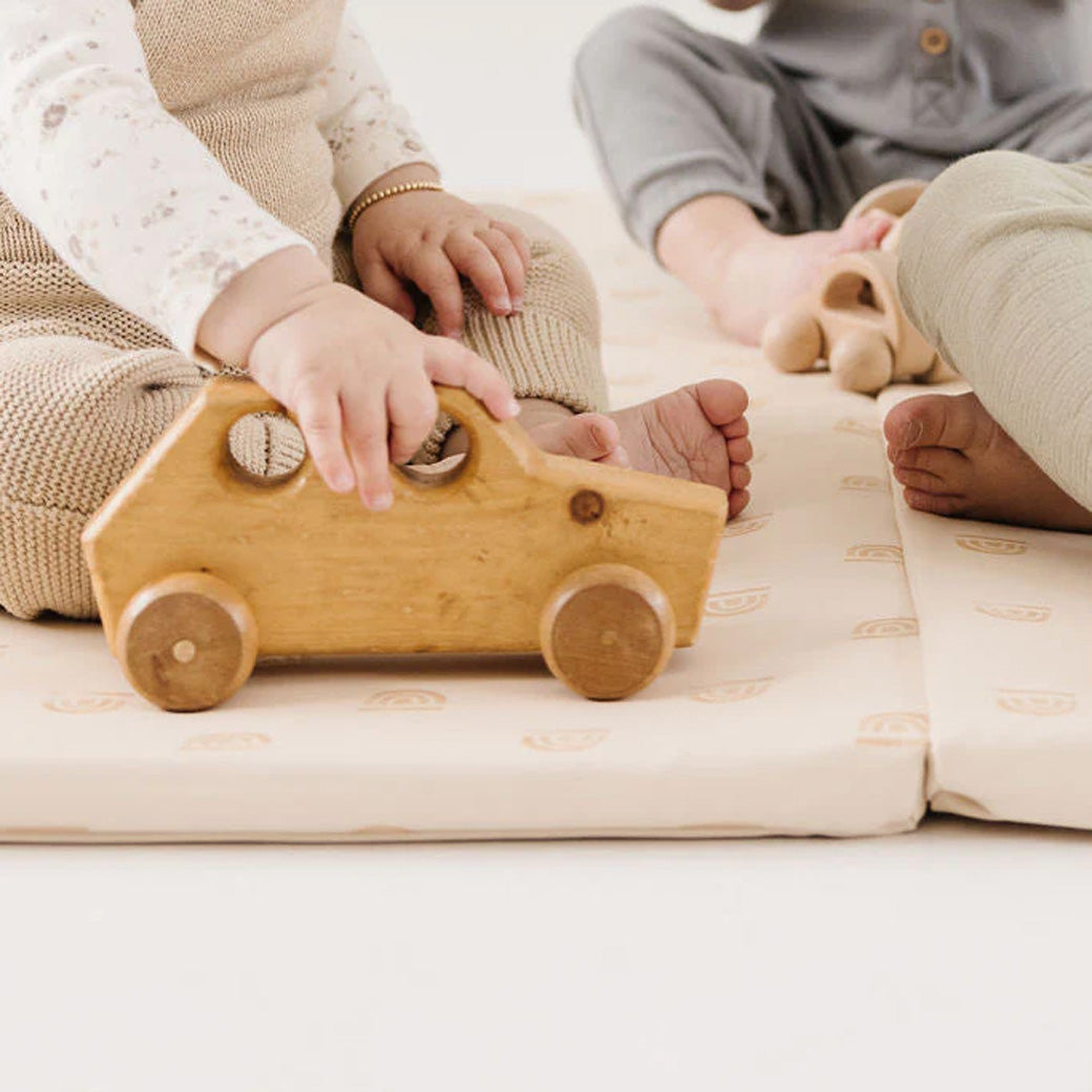 Closeup of kids playing on the Toki Mats Vegan Leather Play Mat in -- Color_Rainbow Cream