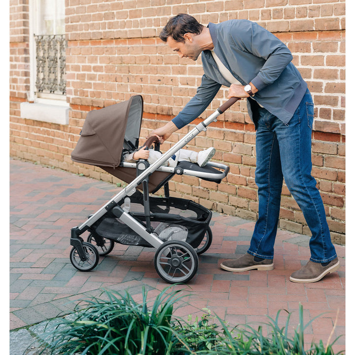 Dad walking down the street with baby in UPPAbaby CRUZ V2 Travel System stroller in -- Color_Theo