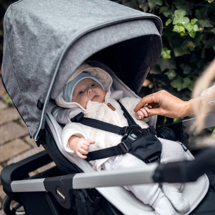 A close up of a newborn in the Thule Shine Bassinet on the Thule Shine Stroller in Grey Melange