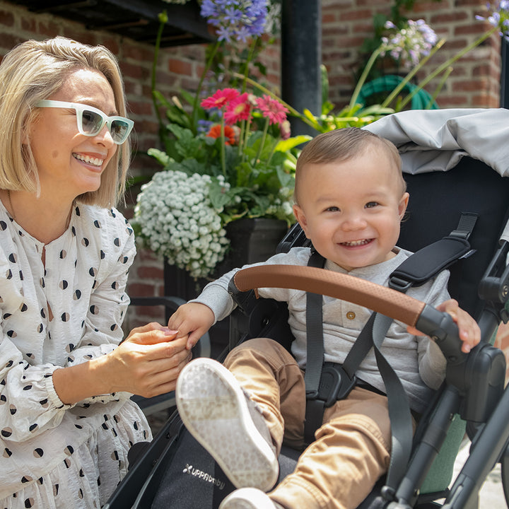 Smiling baby next to mom sitting in the UPPAbaby VISTA V2 Travel System stroller in -- Color_Gwen