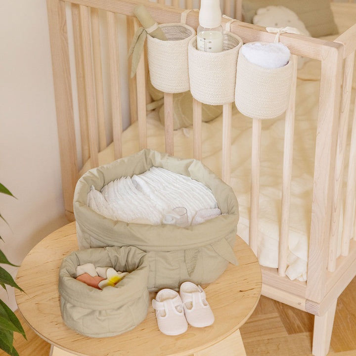 Lorena Canals Bambie Quilted Baskets on a table next to crib  in -- Color_Olive