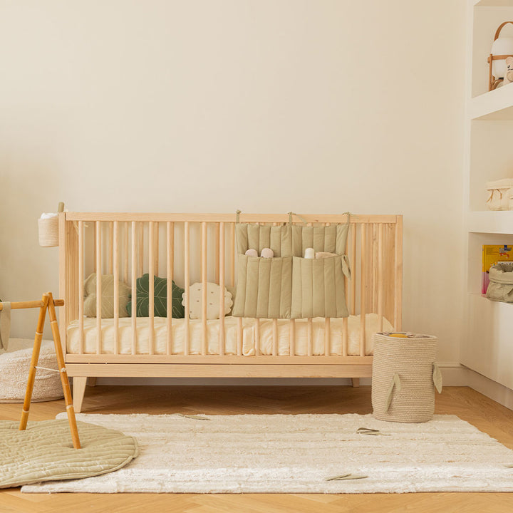 Lorena Canals Bamboo Cane Basket on a rug next to a crib 