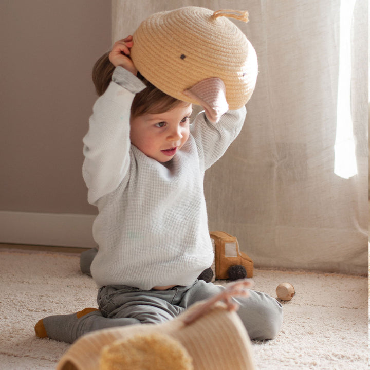 A child putting the top of the Lorena Canals Charlie the Chicken Basket  on his head