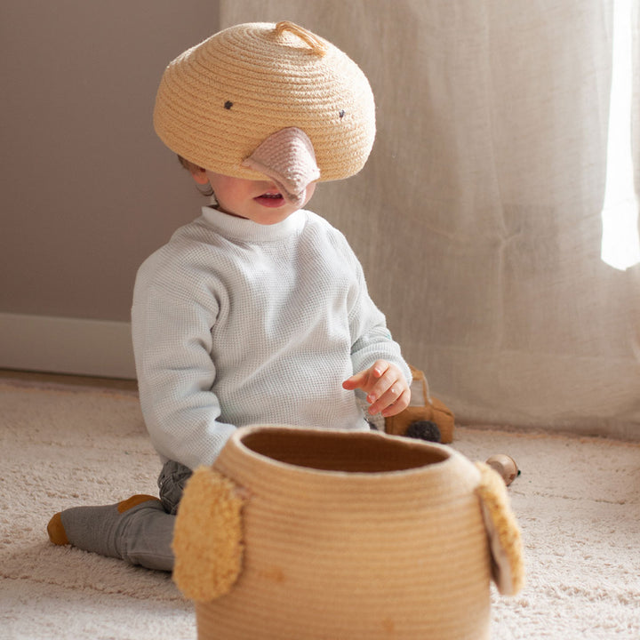 A child with the top of the Lorena Canals Charlie the Chicken Basket  on his head