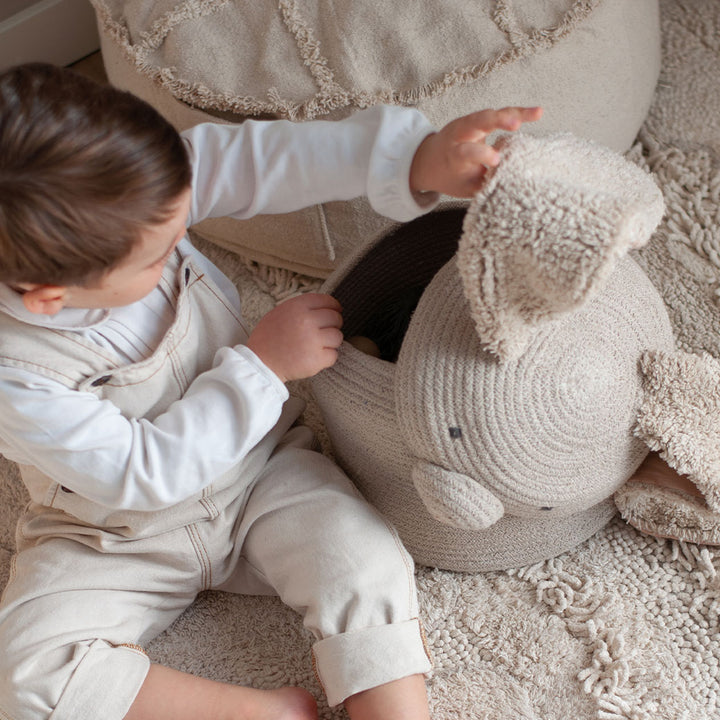 A child sitting next to and looking inside of the Lorena Canals Rita the Rabbit Basket